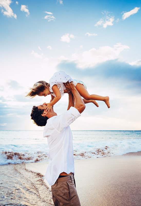 健康慈爱的父亲和女儿一起在海滩上玩耍