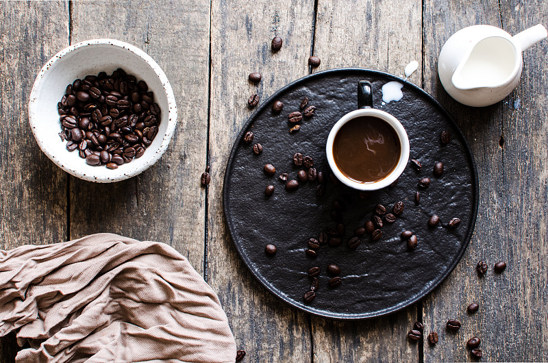 把牛奶从罐子里倒进一杯浓咖啡里