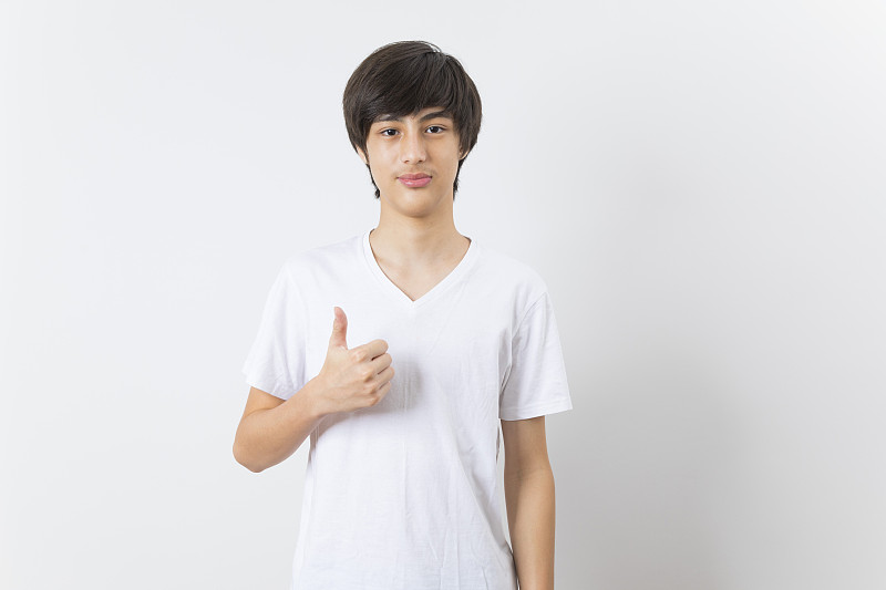 快乐随意的年轻男孩显示拇指在白色的背景。