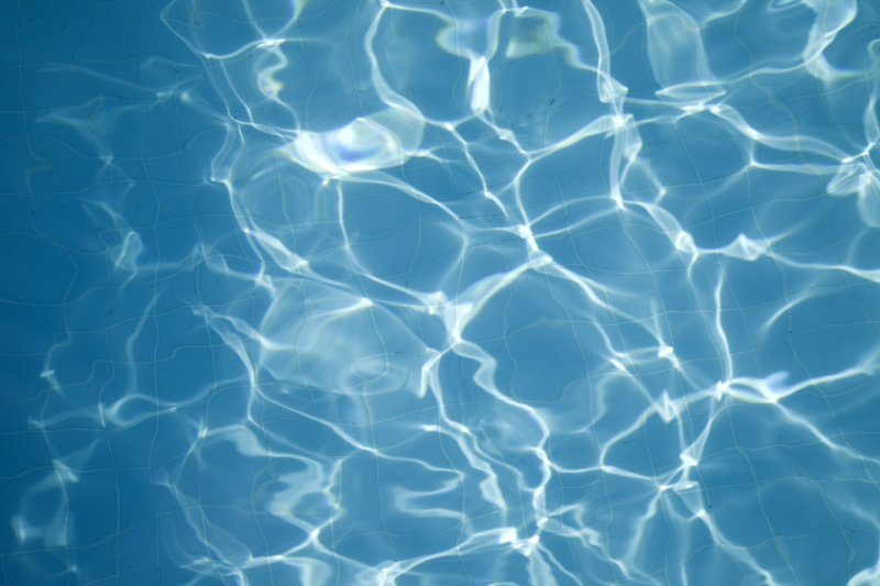 头顶上的太阳反射在蓝色的水在一个游泳池