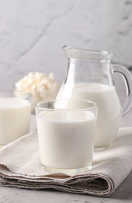 发酵饮料艾兰在玻璃，牛奶在壶和凝乳在碗浅灰色背景，垂直格式