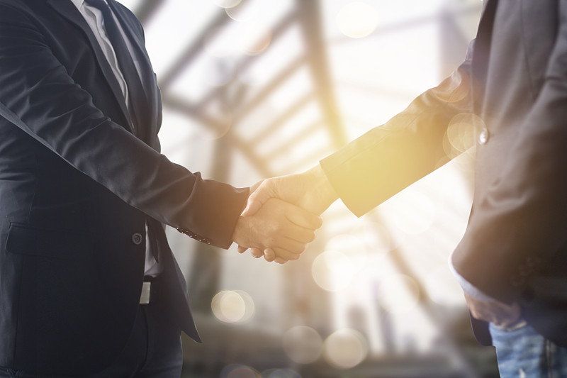 成功的商务谈判理念，商务人士在完成会议后握手或设定目标，规划方式，在成功门前搭建