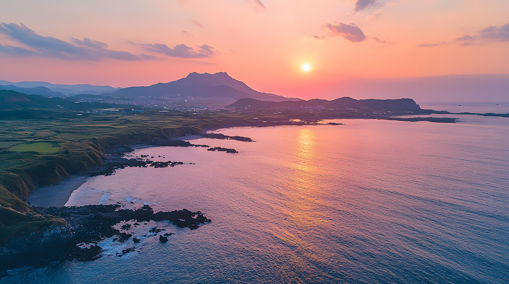 夕阳西下，海面波光粼粼，山峦与海岸线交织在一起