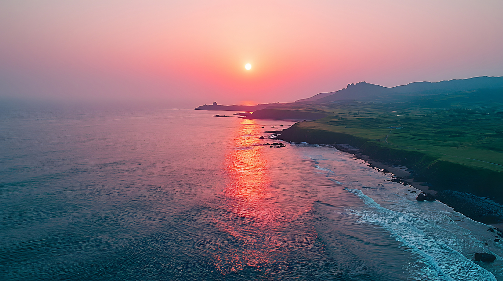 夕阳西下，海面波光粼粼，山峦与海岸线交织在一起
