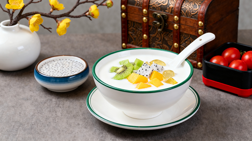 美味水果捞鲜奶碗碗里装着鲜奶上面点缀着猕猴桃芒果火龙果等水果