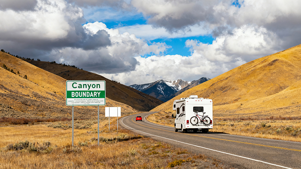 蜿蜒的公路穿过开阔的山谷两侧是山丘公路上行驶着一辆白色的房车