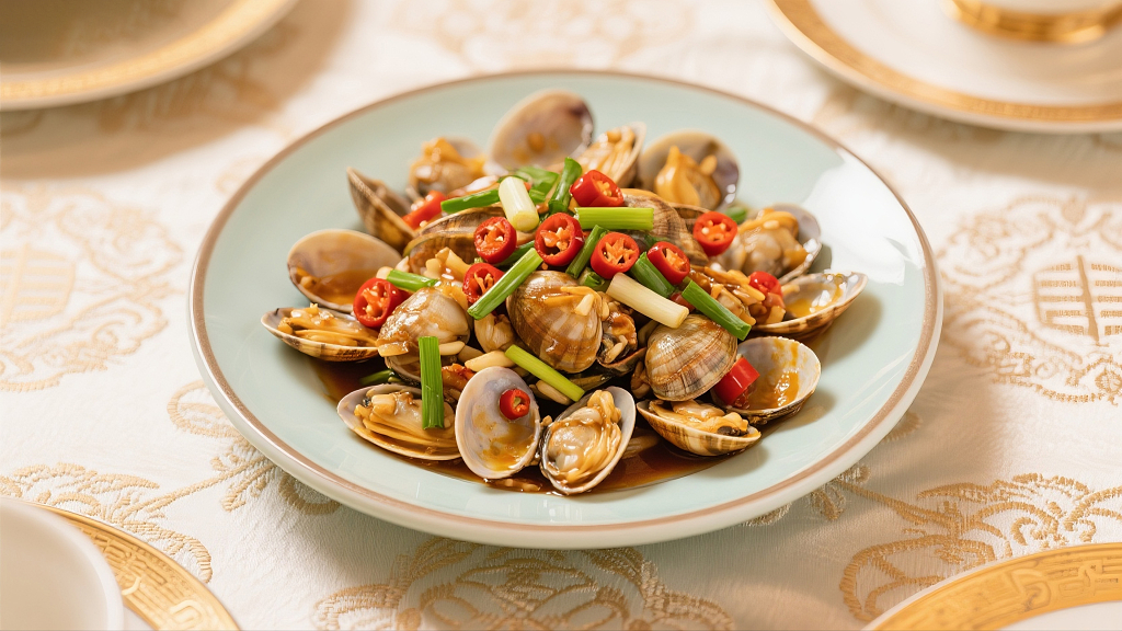 一个盘子里放着刚出锅的炒花蛤美食美味