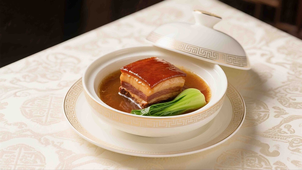 一个白瓷碗里放着一块刚做熟的东坡肉美食美味