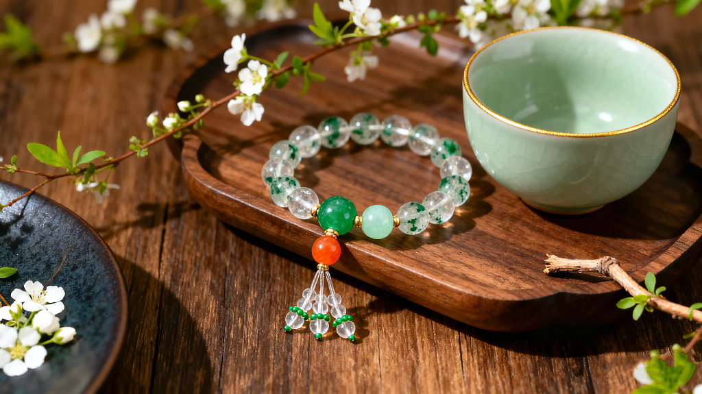一个摆放在木质托盘上的精美手链氛围宁静雅致浅绿色的陶瓷茶杯