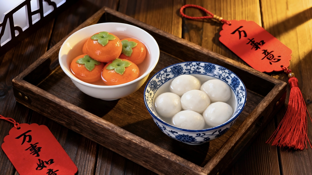 两碗造形不同的汤圆在木质托盘里柿柿如意团团圆圆