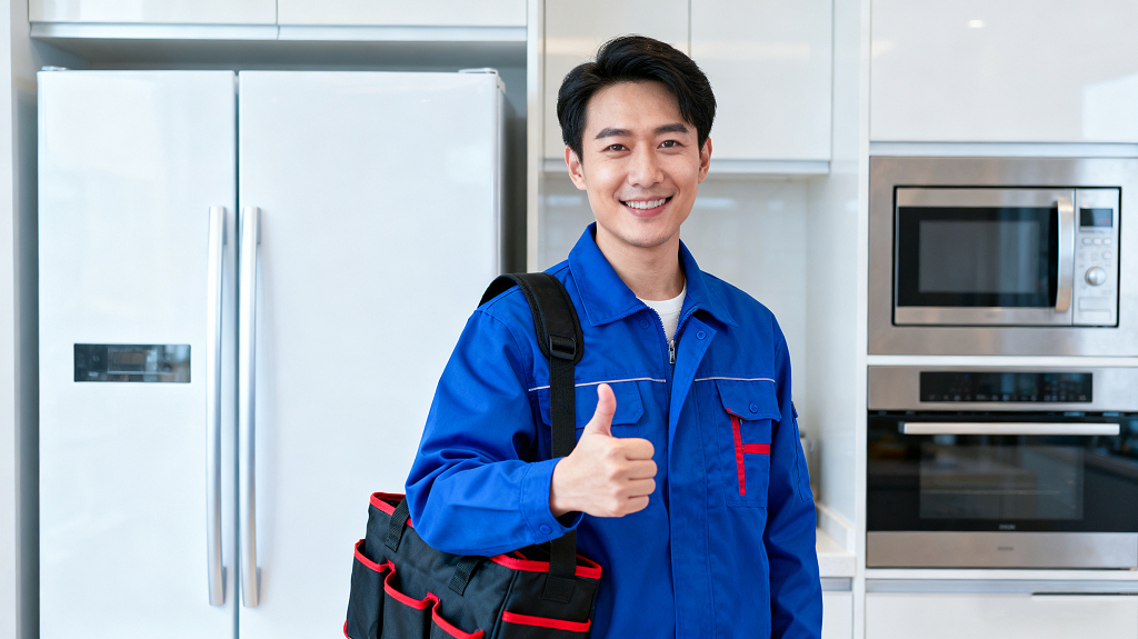 家电维修员穿蓝色工装背工具包在厨房竖大拇指微笑服务职业形象