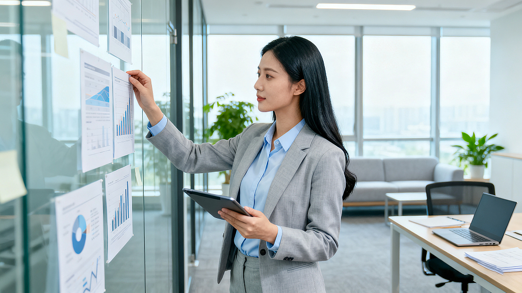 职场女性身着西装办公室查看数据图表手持平板商务数据分析场景