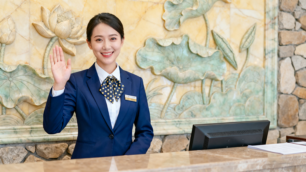 酒店前台人员穿蓝色西装挥手迎宾服务热情职业装接待职场女性