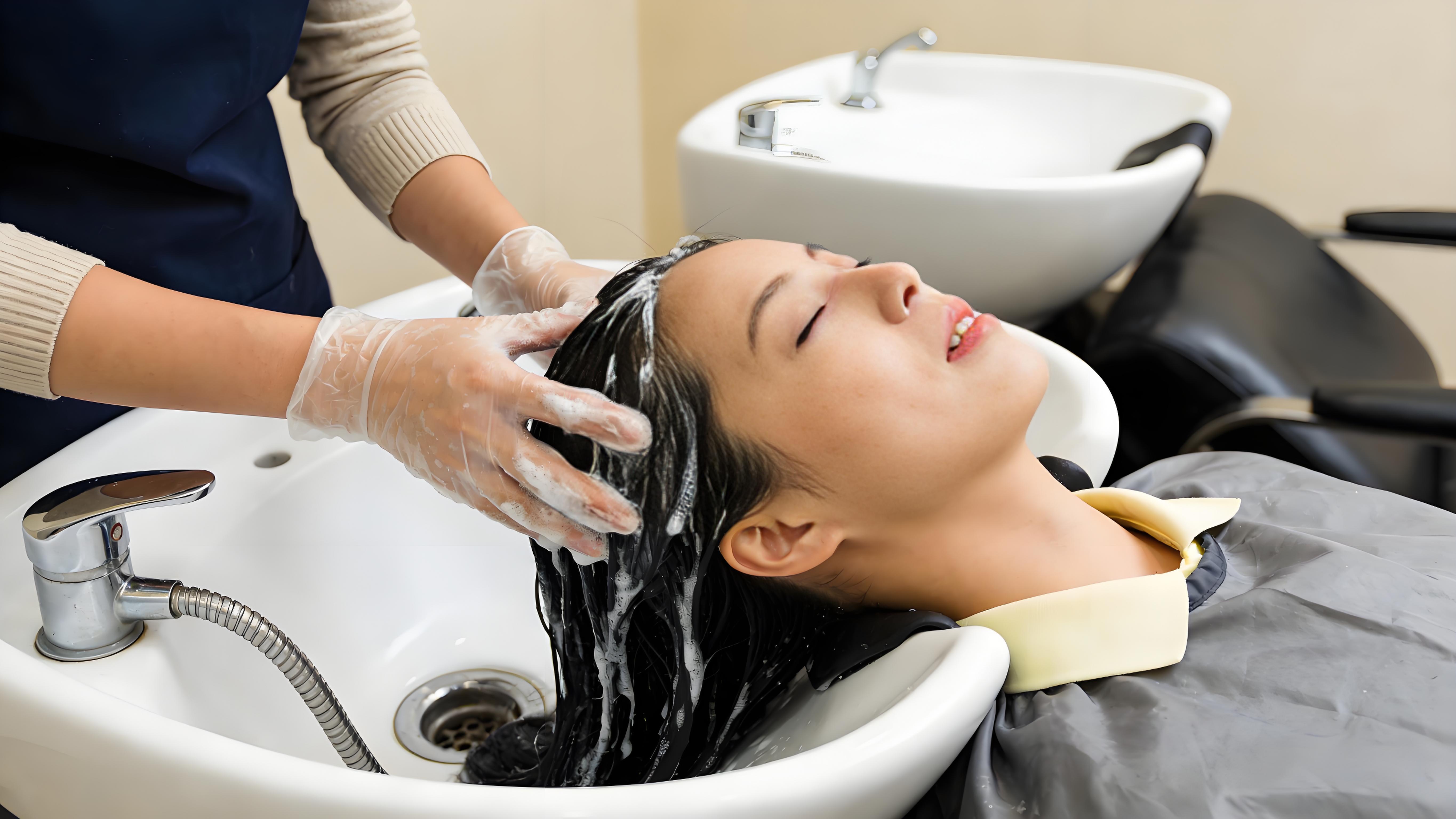 美发店洗发场景技师戴手套为躺姿女士清洗头发