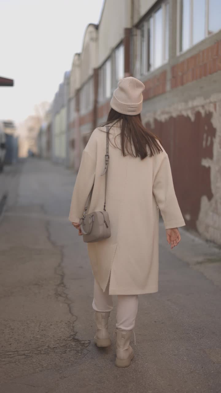 时尚的女人走在一条门面破败的狭窄街道上