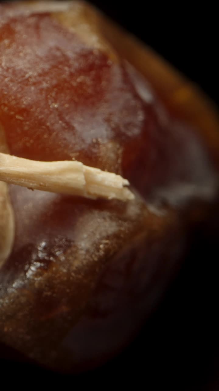 黑桌子上的干枣子有镜像。多莉滑块极端特写。垂直视频。