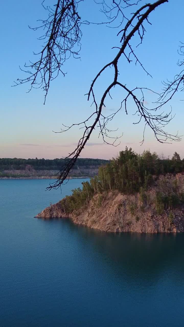 夏天的风景。在一个阳光明媚的夏日夜晚，看到一个湖水湛蓝的湖泊。垂直视频