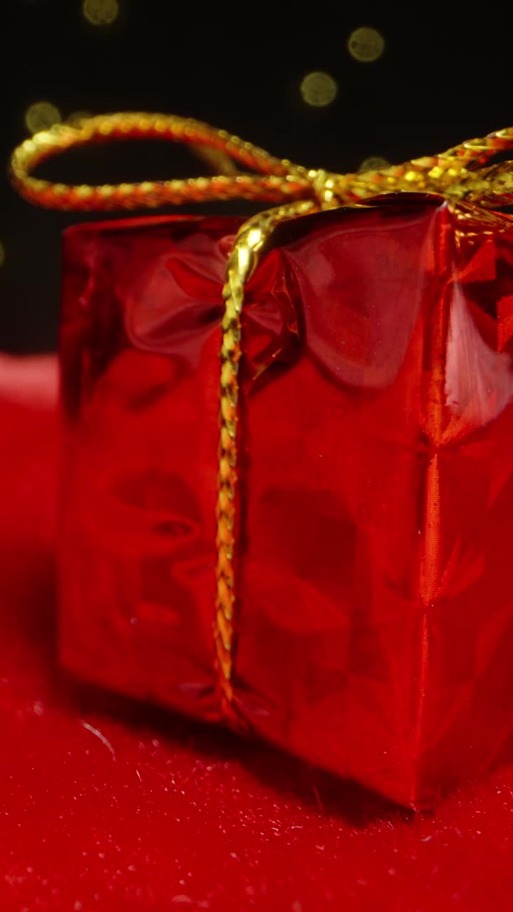 垂直视频。在花环的背景下，一个红色的小礼盒上有一个蝴蝶结。