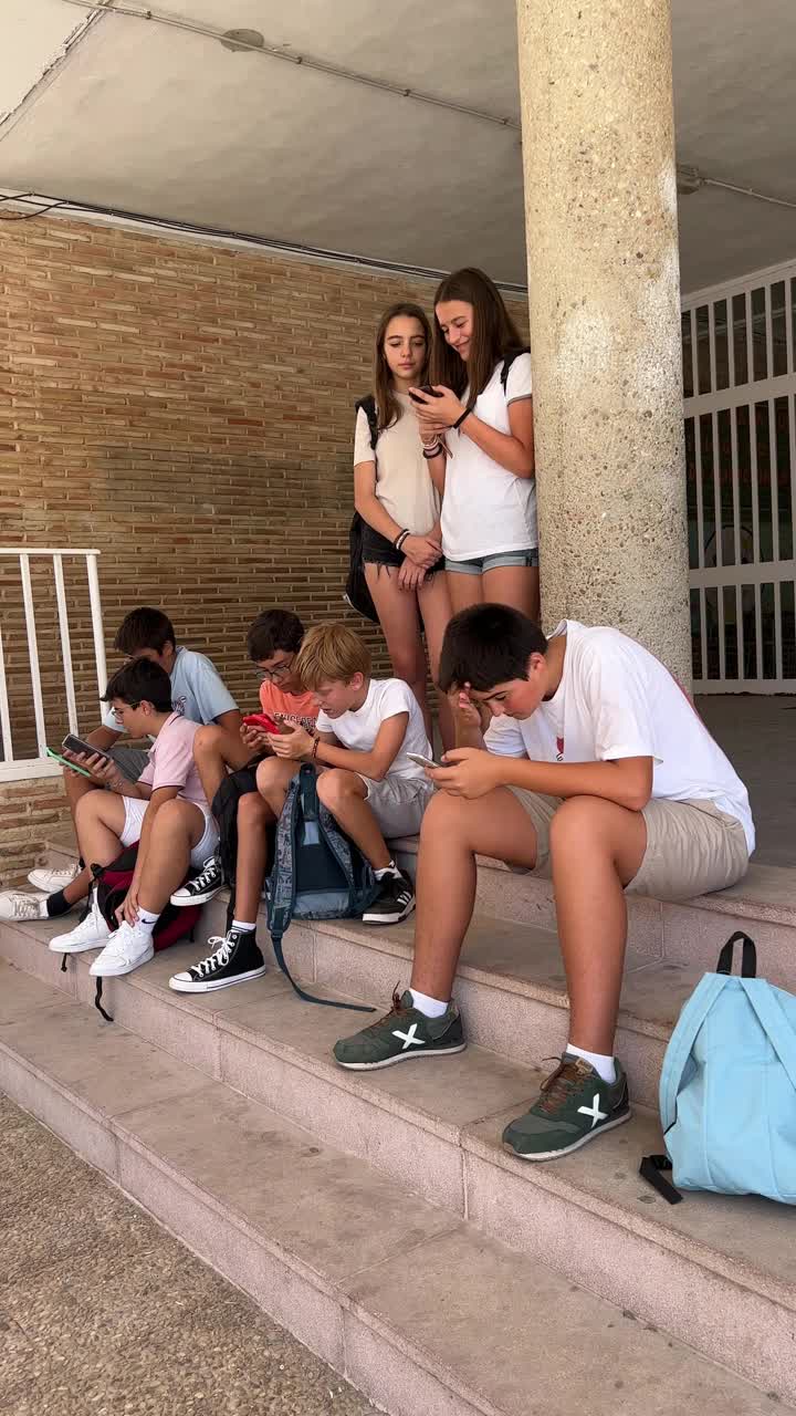 一群学生在校门口玩手机。