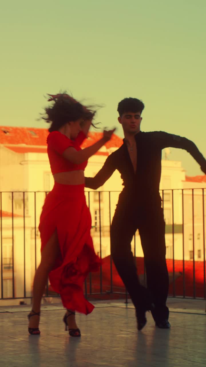 垂直画面:一对情侣在城外跳拉丁舞，背景是古城。两名专业舞蹈演员在日落时的性感舞蹈，在古代文化丰富的旅游景点。