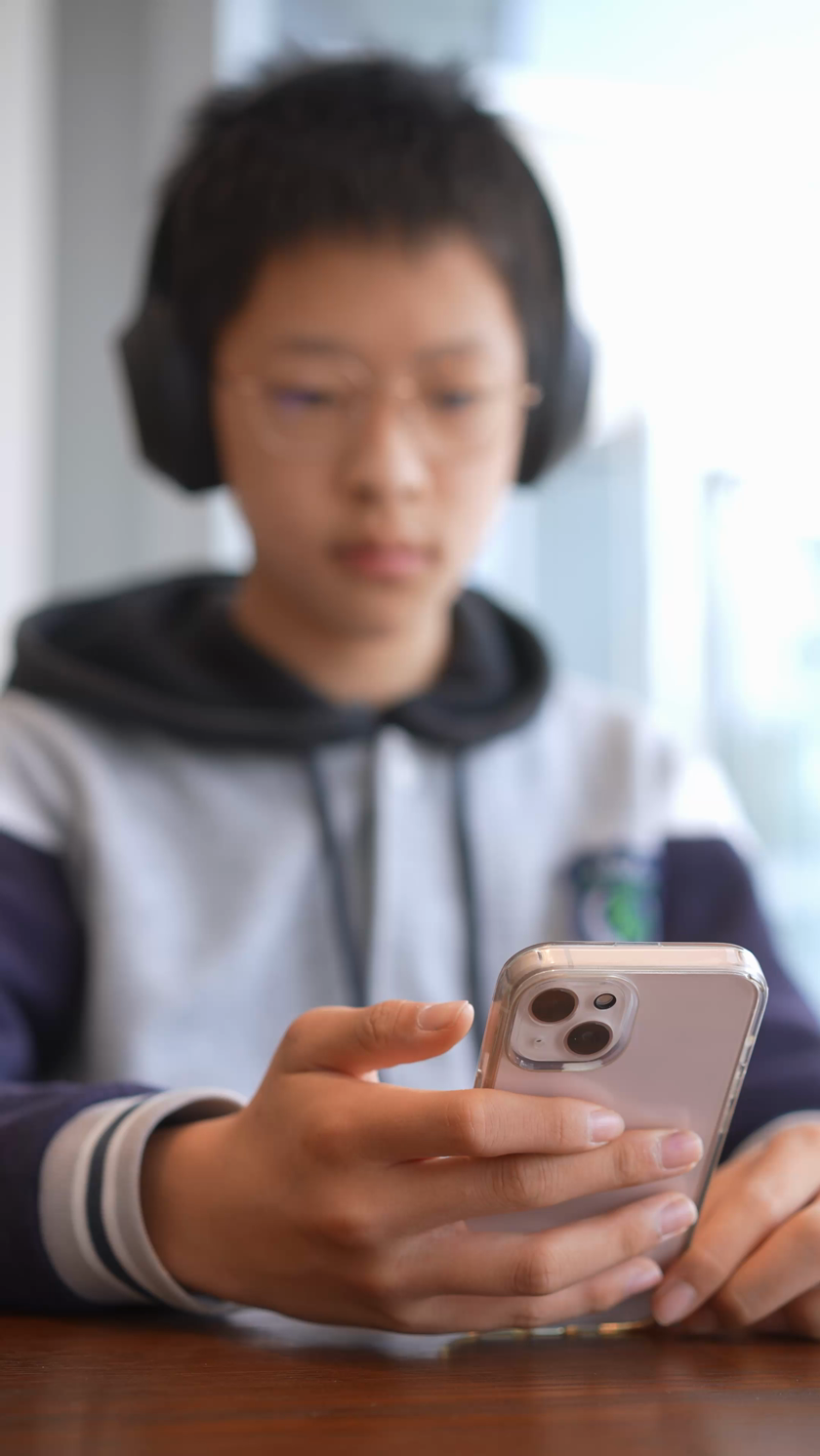 学生在咖啡厅戴着耳机低头玩手机竖屏