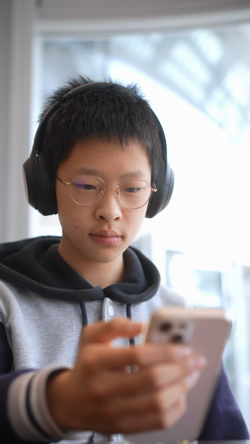 学生在咖啡厅戴着耳机玩手机竖屏